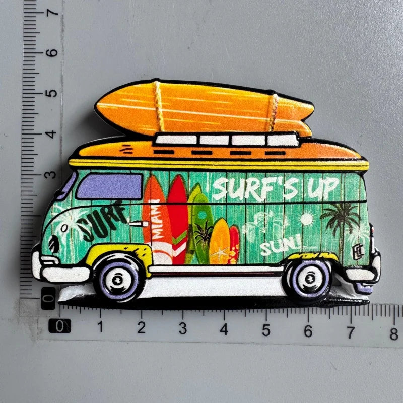 A colorful magnet shaped like a yellow van with a surfboard on the roof and tropical foliage.
