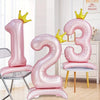 Pink aluminum foil crown number balloons shaped like 1, 2, and 3 displayed in a bright room.