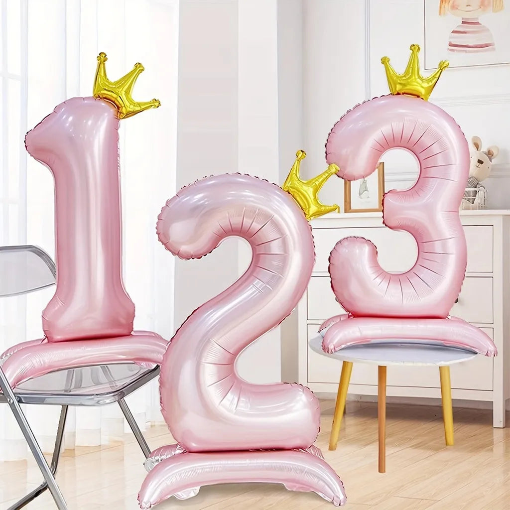 Pink aluminum foil crown number balloons shaped like 1, 2, and 3 displayed in a bright room.