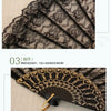 Close-up of a black and beige vintage lace folding fan with intricate patterns and gold accents.