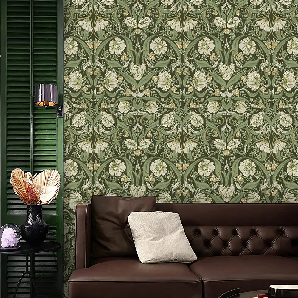 Un canapé en cuir marron foncé devant un mur recouvert de papier peint floral vert et crème.