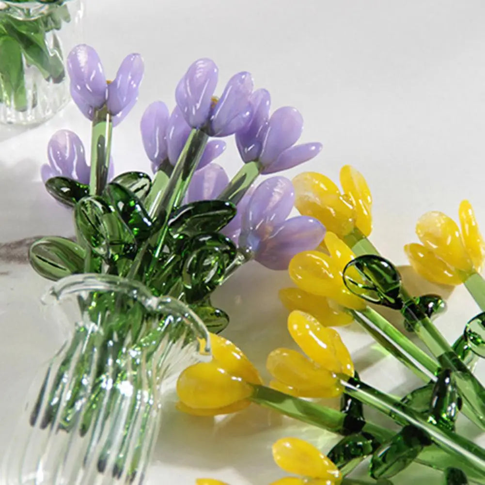 A bouquet of hand-blown glass flowers featuring purple and yellow tulips in a clear glass vase.