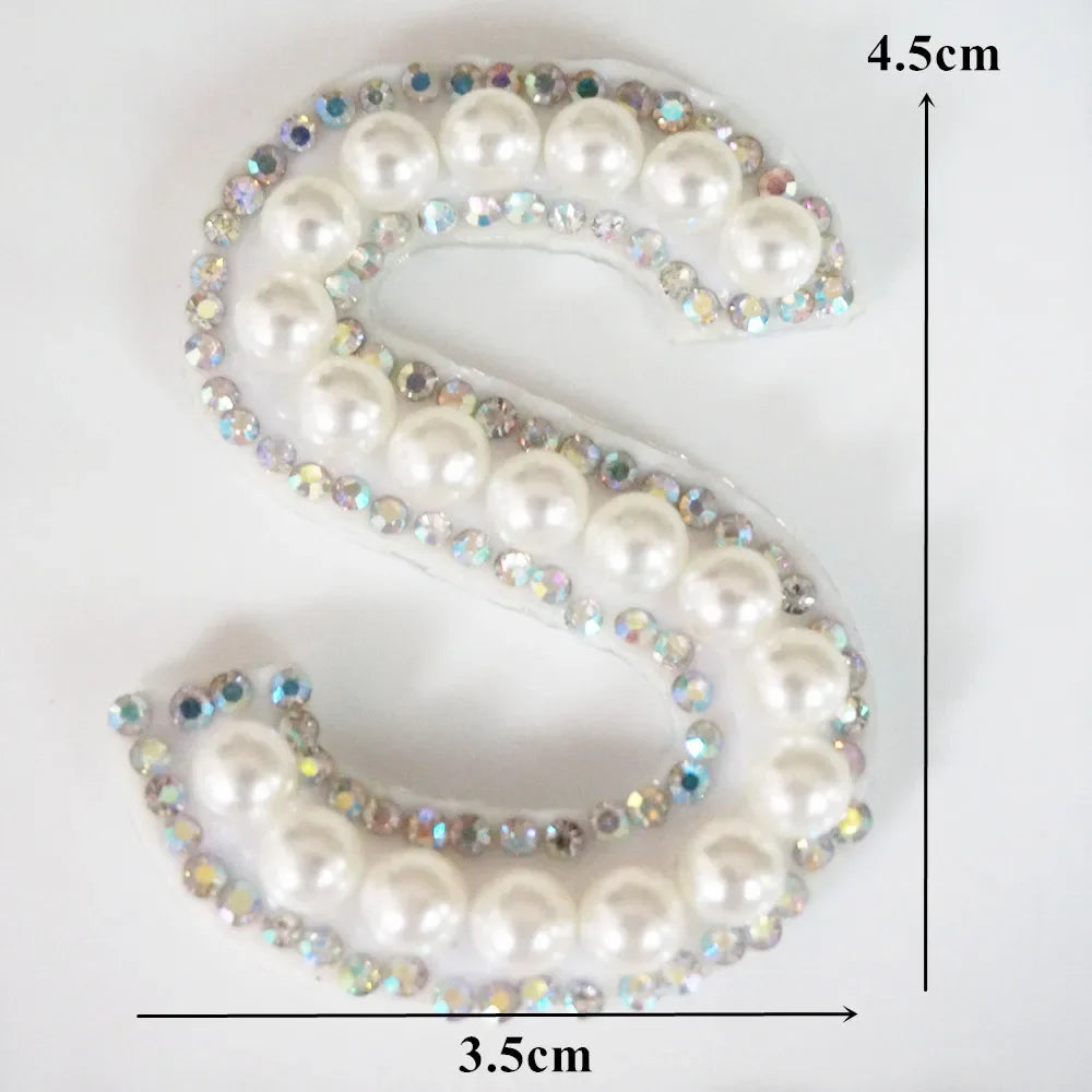 A white alphabet letter S made of pearl and rhinestone patches, measuring 4.5cm high and 3.5cm wide.