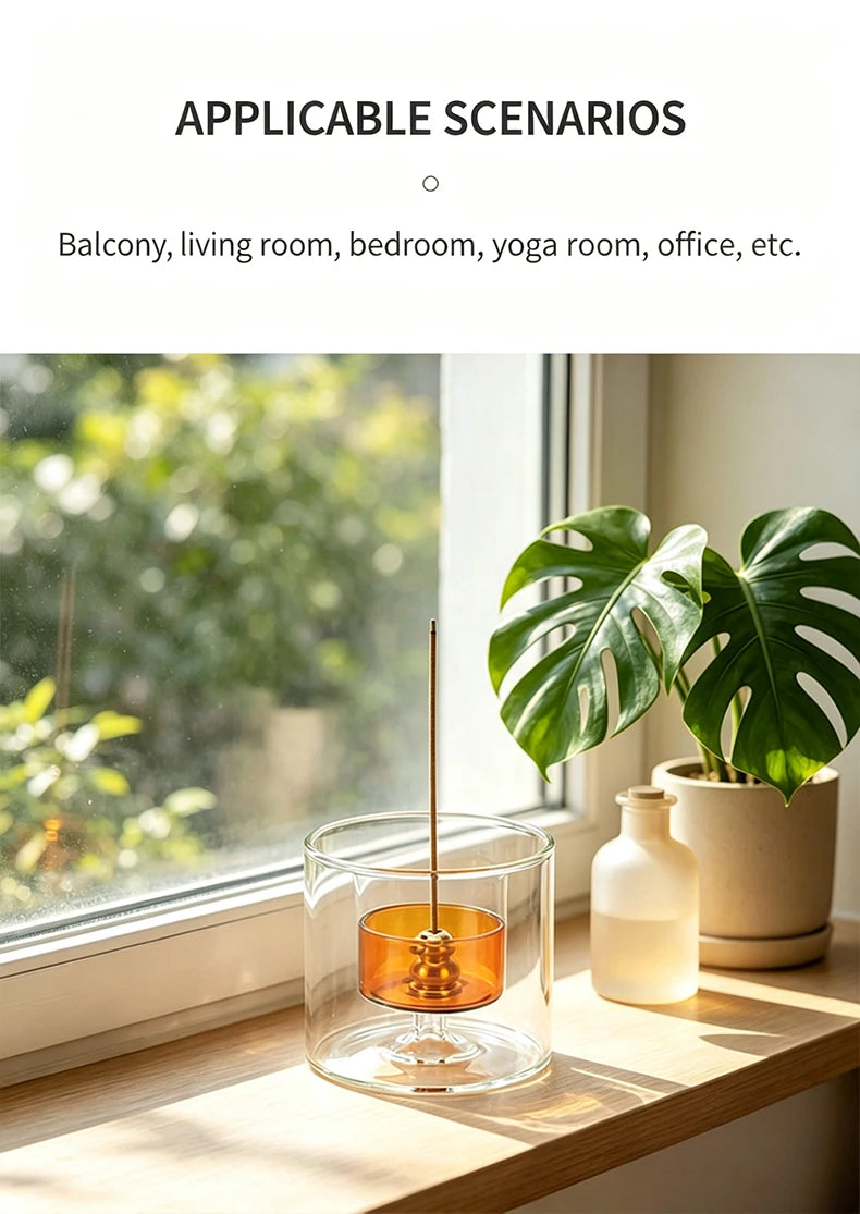 A clear gourd-shaped glass incense burner with a metal stick and ash catcher sits on a wooden windowsill next to a potted pla