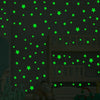 A wall decorated with green glow-in-the-dark star decals in a bedroom setting.
