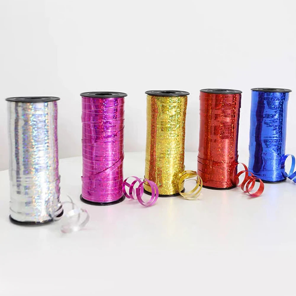 A collection of glitter curling ribbon rolls in various colors including silver, pink, gold, red, and blue.