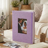 A purple linen photo album with a square photo insert resting on a wooden surface.