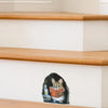 A cartoon mouse is shown reading a book on a white wall shelf next to wooden stairs.