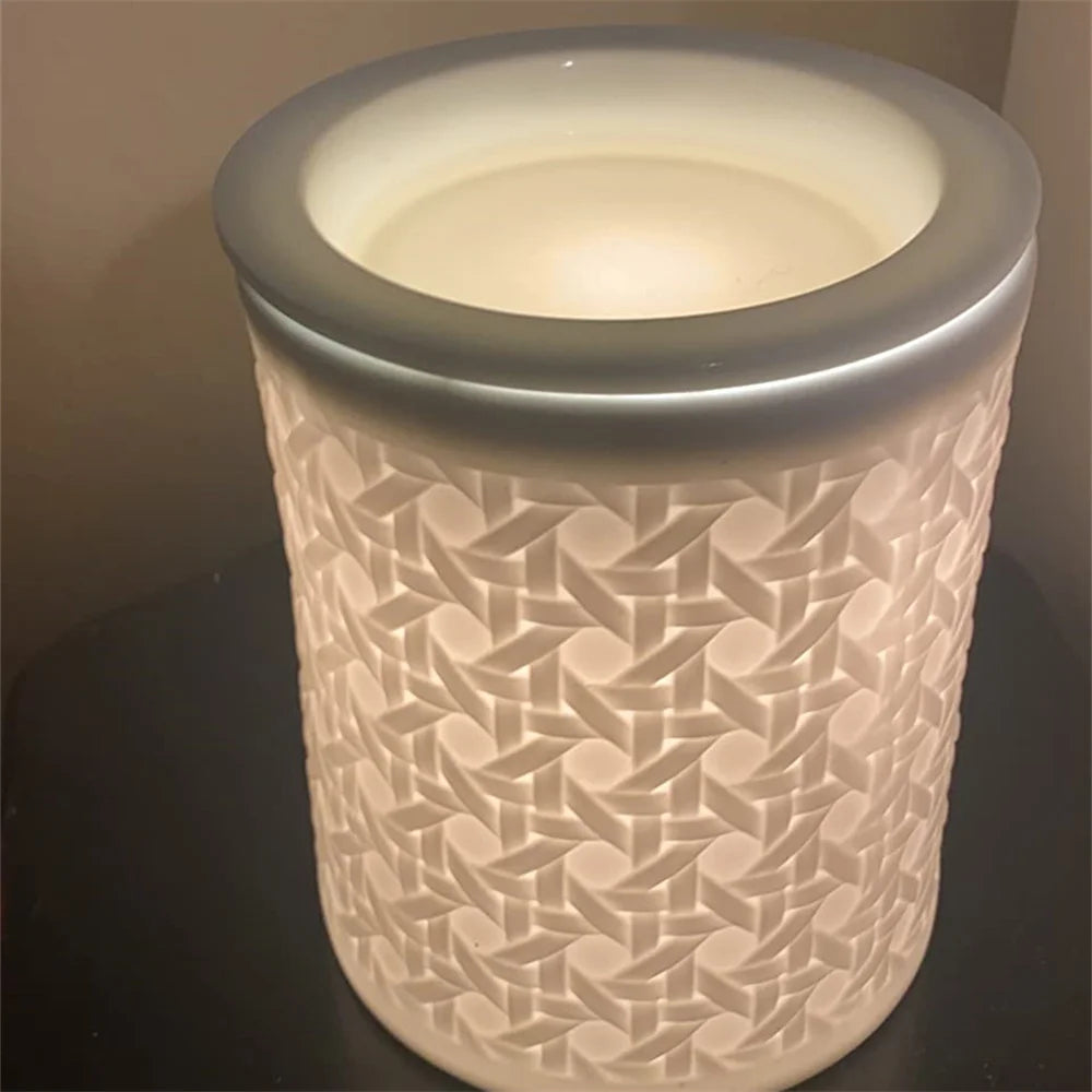 A cylindrical white wax warmer with a textured pattern and a frosted glass light bulb inside.
