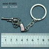 A miniature alloy gun model keychain with a silver finish and a silver ring, measured against a ruler.