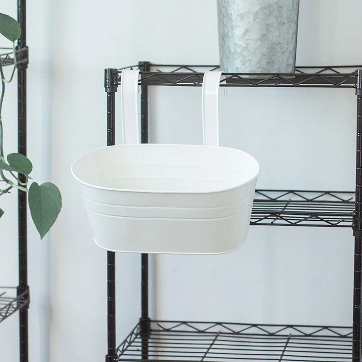 A white rectangular planter is displayed on a black metal shelving unit.