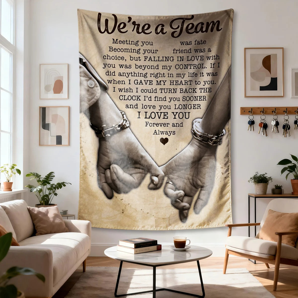 A large fabric wall tapestry featuring the text We're a Team and an illustration of two hands clasped together.