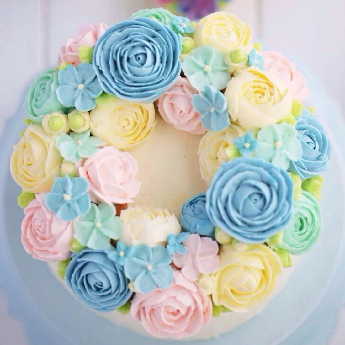 A colorful arrangement of blue, pink, and yellow rose flowers decorating a cake.