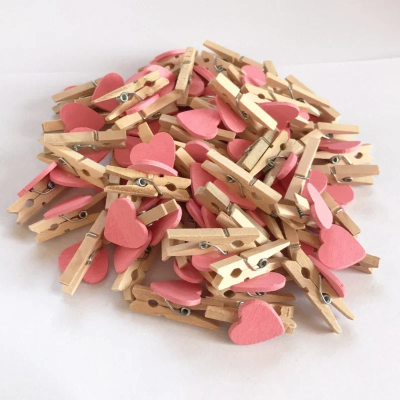 A pile of small pink wooden heart-shaped photo clips used for crafts and display.