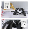 Three heart-shaped resin hand sculptures in gold and black finishes displayed on a white background.