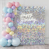 A shimmering silver and purple sequin wall backdrop with Happy Birthday text for a party decoration.