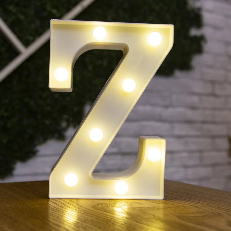 A glowing warm white LED alphabet letter light shaped like the letter Z resting on a wooden surface.