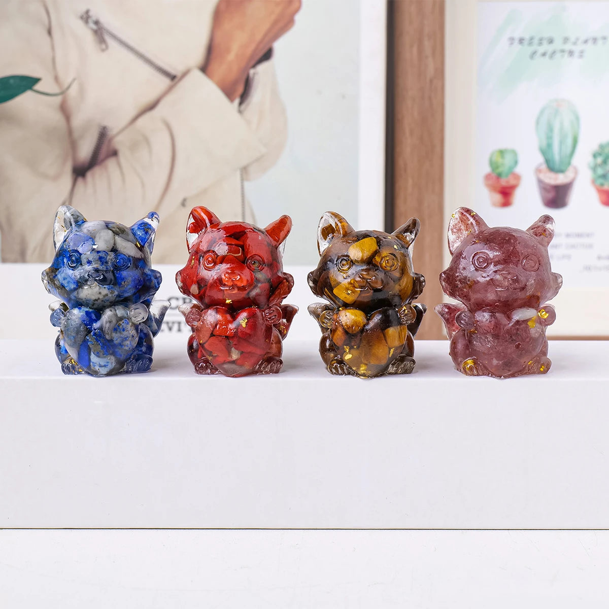 Four natural fox crystal sculptures in various colors and textures displayed on a white surface.
