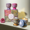 A gift set of three scented candles in decorative tin containers with floral patterns.
