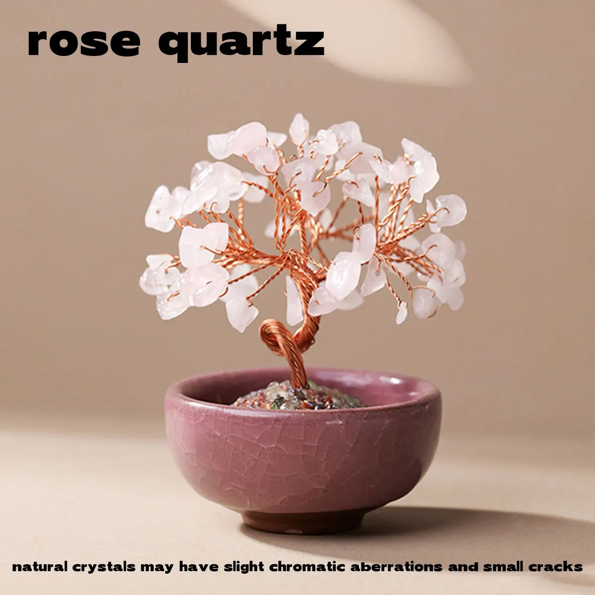 A handcrafted rose quartz crystal tree with a copper wire base growing out of a pink bowl.