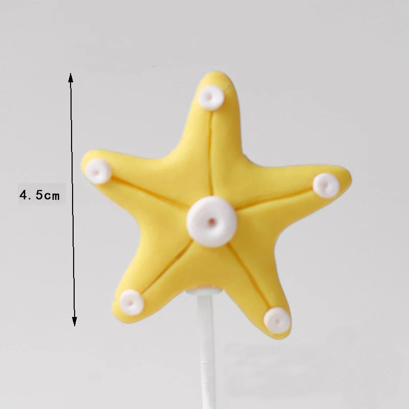 Yellow starfish cake topper with five small white dots on a white stick.