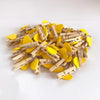 A pile of small, heart-shaped wooden photo clips in yellow and natural wood tones.