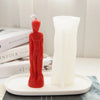 A red silicone mold shaped like a human figure stands next to a white candle mold on a white tray.