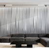 A modern living room featuring a dark gray sectional sofa and coffee table in front of a vertical metallic gold striped wall 