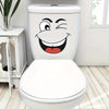 A white toilet with a cartoon face sticker featuring a wide, smiling expression.