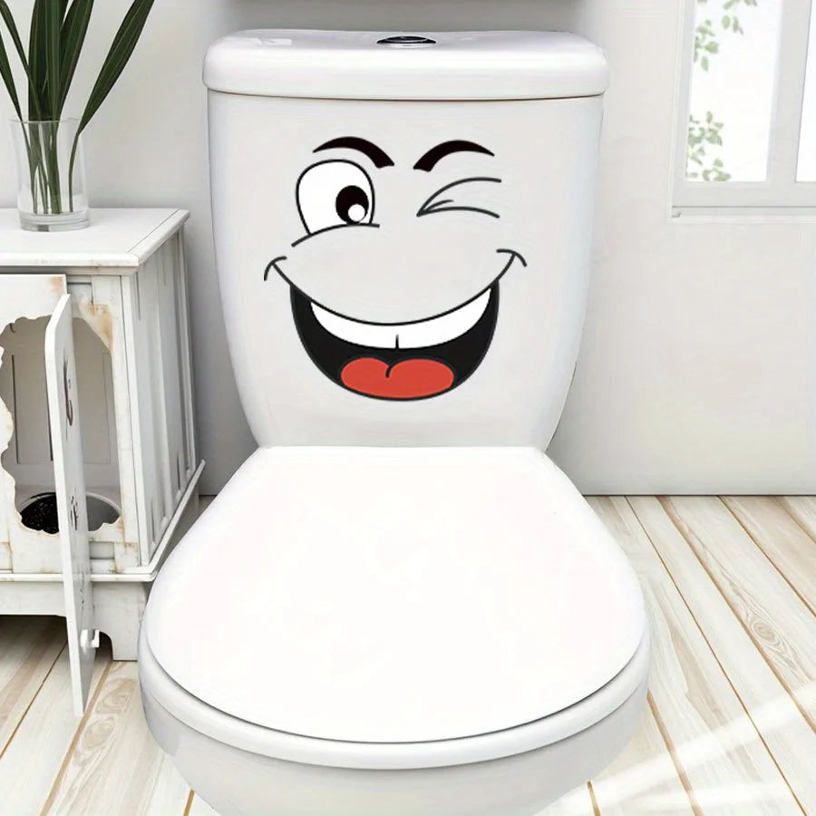 A white toilet with a cartoon face sticker featuring a wide, smiling expression.