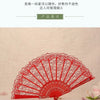 A red lace folding fan is displayed against a light background.