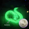 A luminous green snake art model is coiled on a sheet of paper, highlighting its texture and form.
