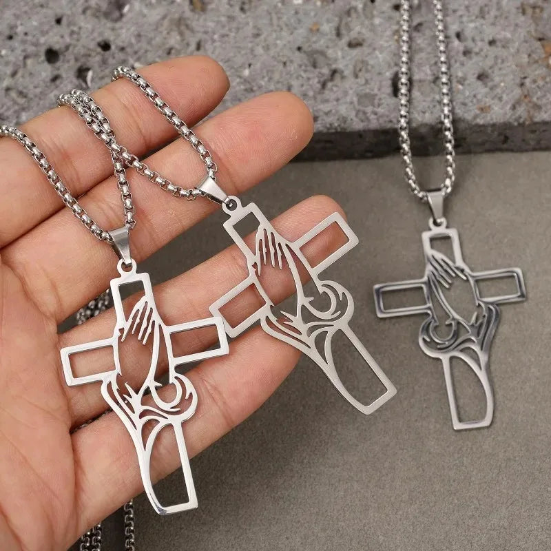 Silver stainless steel praying hands cross pendant necklace displayed in a hand