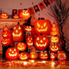 A glowing orange Halloween pumpkin lantern decorated with carved faces sits on a wooden surface.