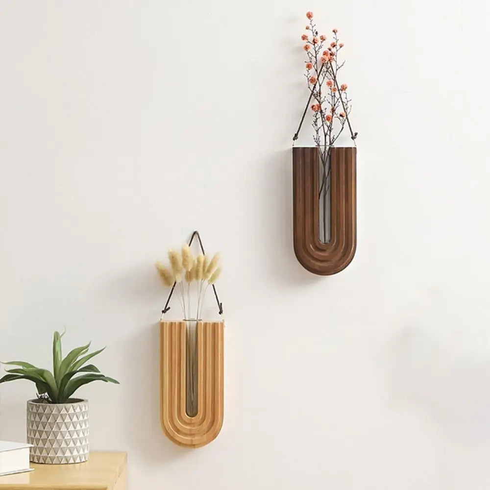 A wooden wall-mounted vase holding a small plant with delicate orange flowers.