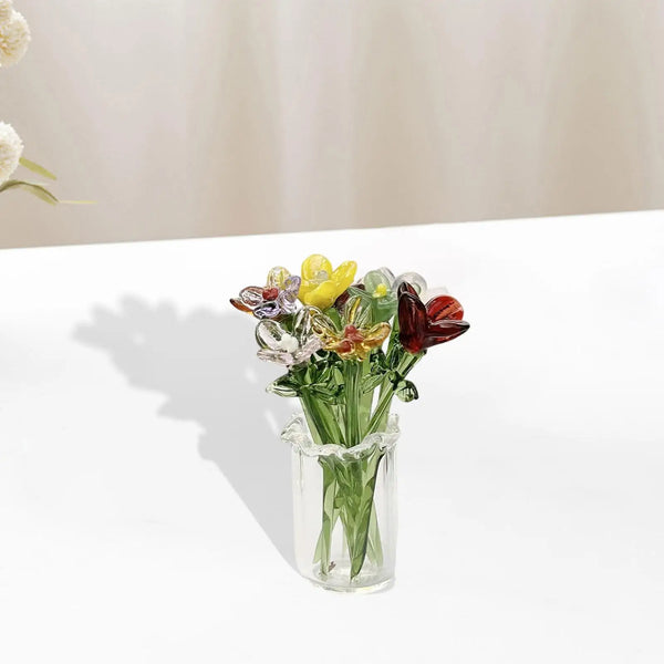 Un petit vase en verre à bulbe rempli de fleurs séchées colorées et de verdure.