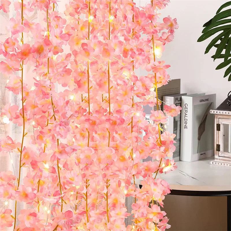 Pink sakura flower garland with glowing lights hanging against a white background.
