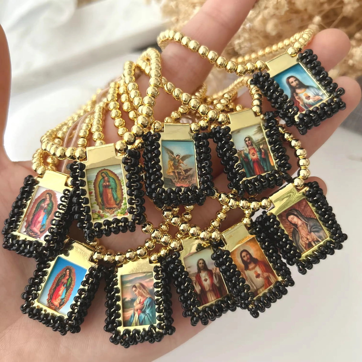 Gold-plated charm bracelet featuring multiple Virgin Mary Guadalupe charms on black cord