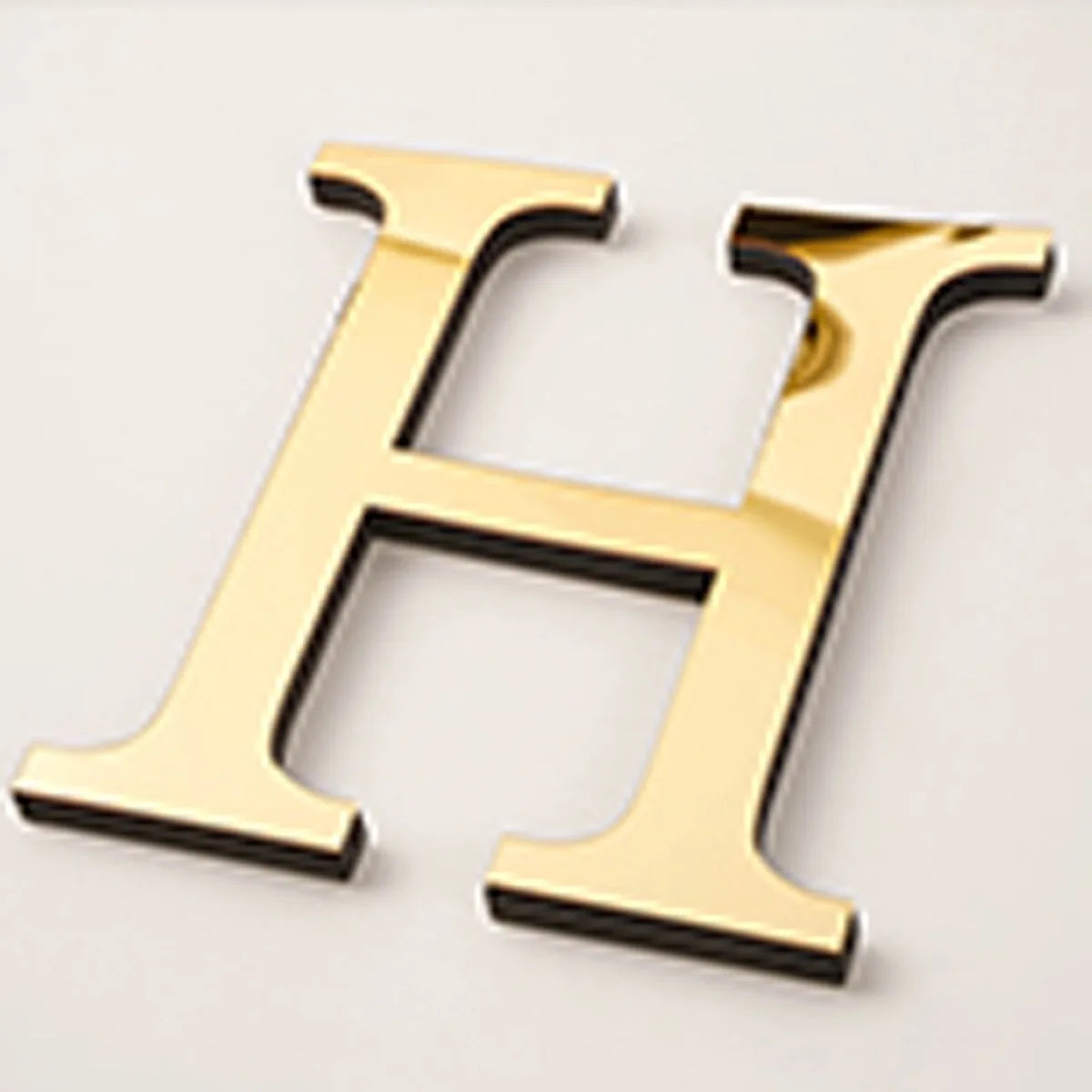A gold acrylic mirror letter H wall sticker for decorative purposes.
