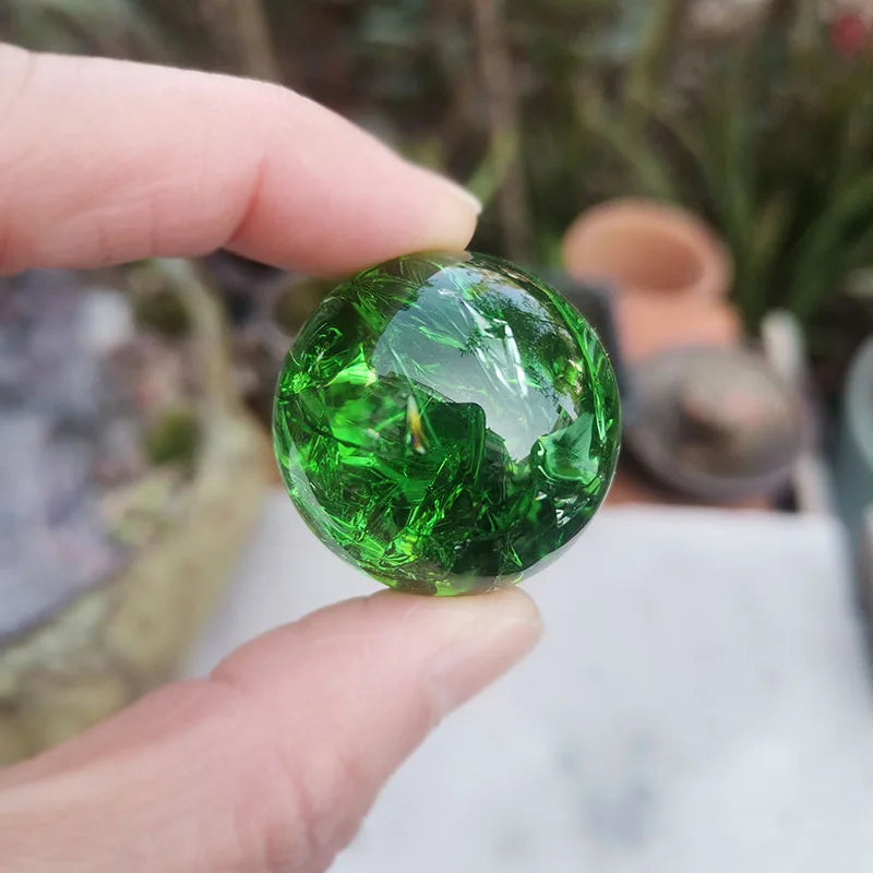 A hand holds a bright green crystal ice crack ball used as water fountain decor.