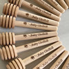 A set of ten natural wood honey dipper sticks engraved with Baby Gledhill
