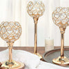 A close-up of a golden crystal candle holder with a decorative spherical design resting on a wooden surface.