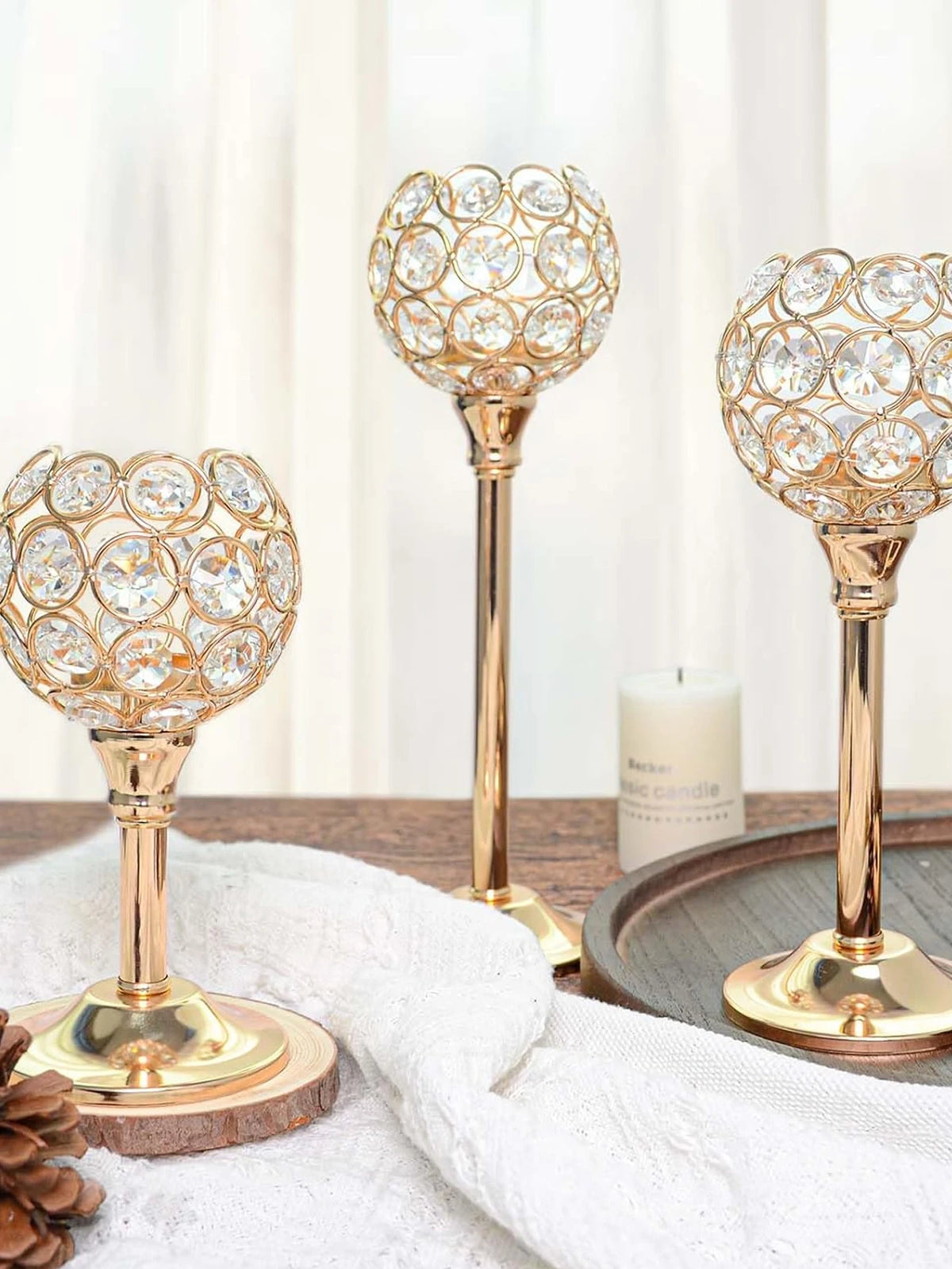 A close-up of a golden crystal candle holder with a decorative spherical design resting on a wooden surface.