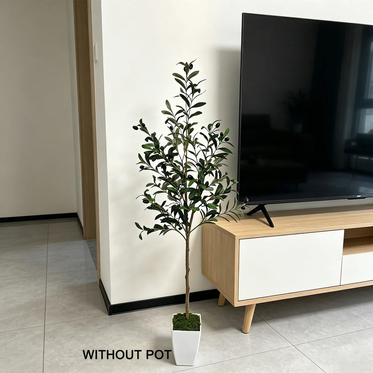 A lifelike artificial olive tree in a white pot displayed next to a large black television on a wooden cabinet.
