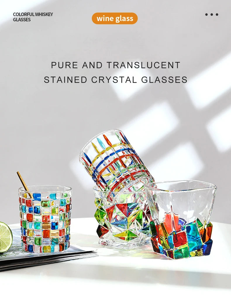 A collection of pure and translucent stained crystal whiskey glasses with various facets and colors.
