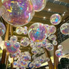 A cluster of iridescent, holographic foil balloons suspended from the ceiling.
