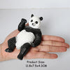 A realistic black and white panda figurine is held in a person's hand.