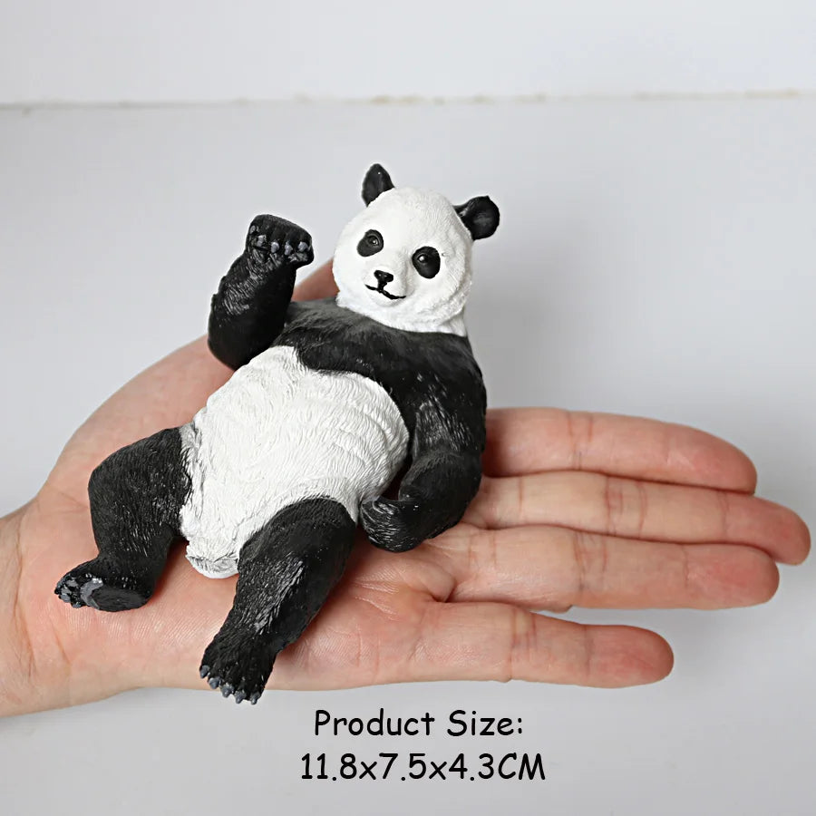 A realistic black and white panda figurine is held in a person's hand.