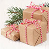 A stack of brown gift boxes tied with red and white striped cotton baker's twine.