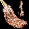 A close-up of lighted tinsel wedding wands with LED glow hanging against a black background.